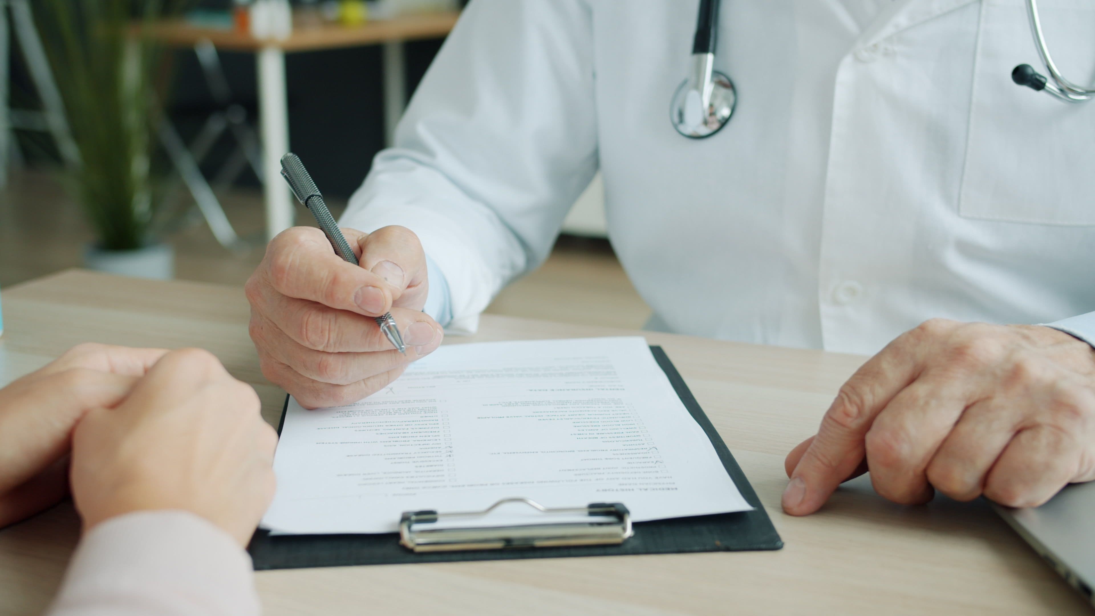 Doctor completing a form on a clipboard